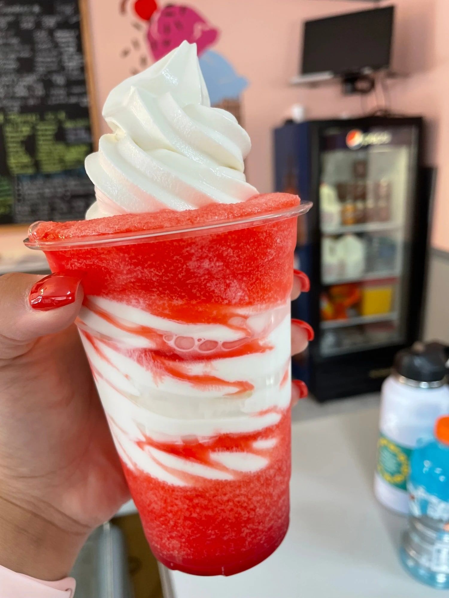 A cherry Screamer, slushie swirled with vanilla soft serve, held up in the shop