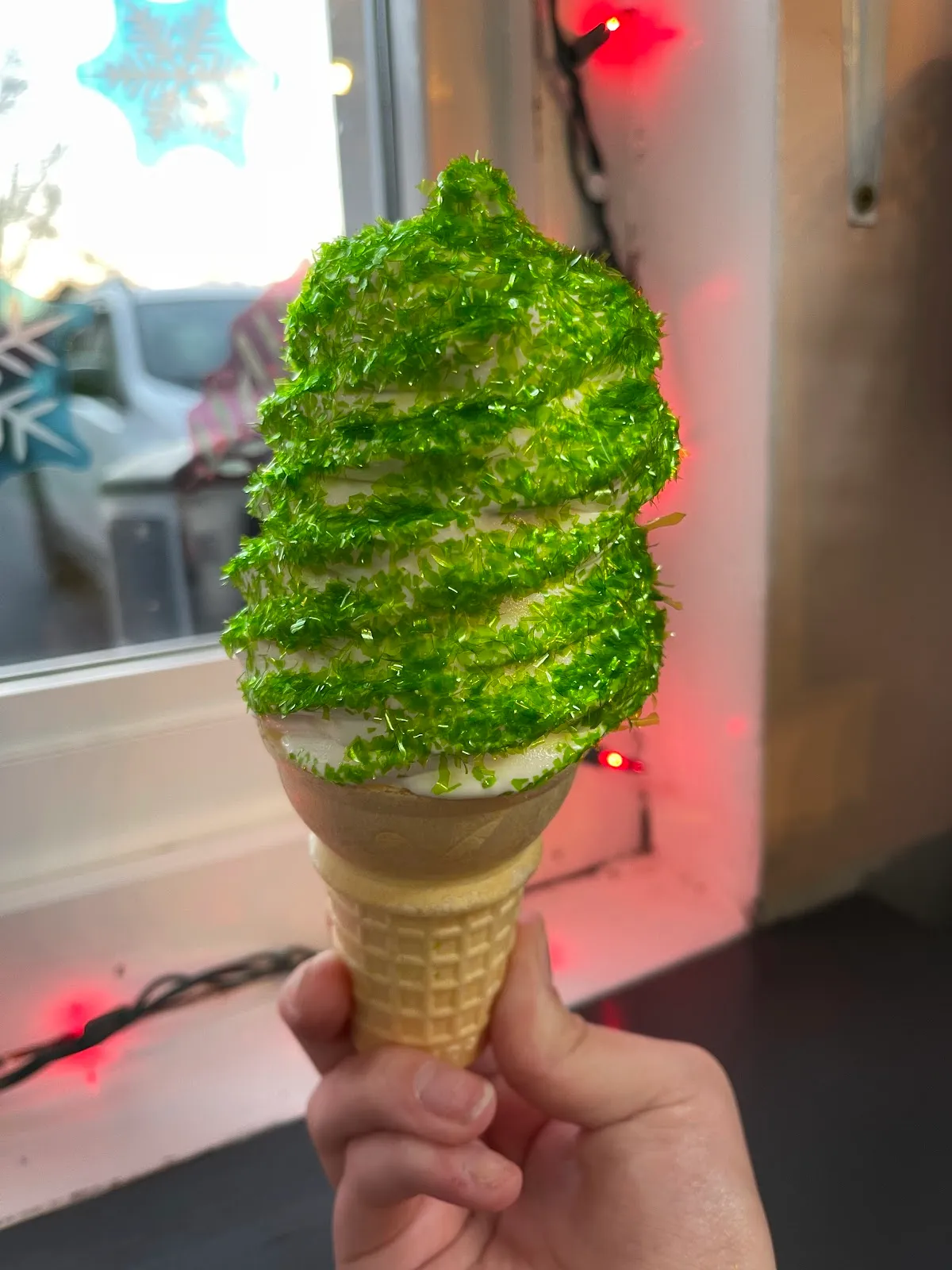 A soft serve cone dipped in green glitter sugar